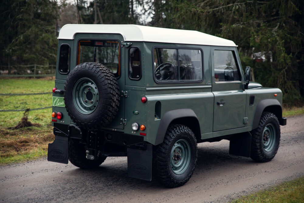 Green classic Land Rover Defender on a rural road