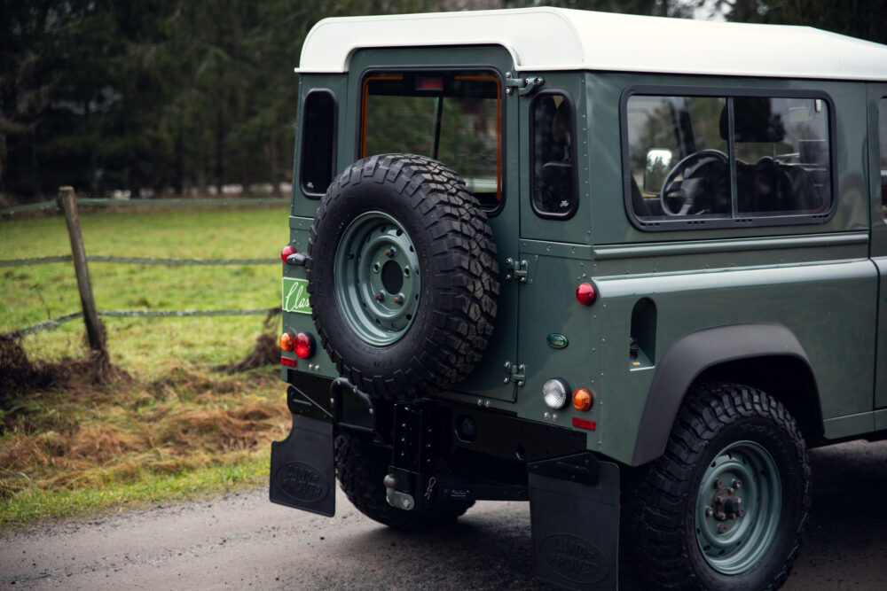 Green vintage Land Rover with spare tire outdoors