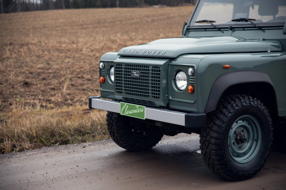 Green Land Rover Defender on rural road