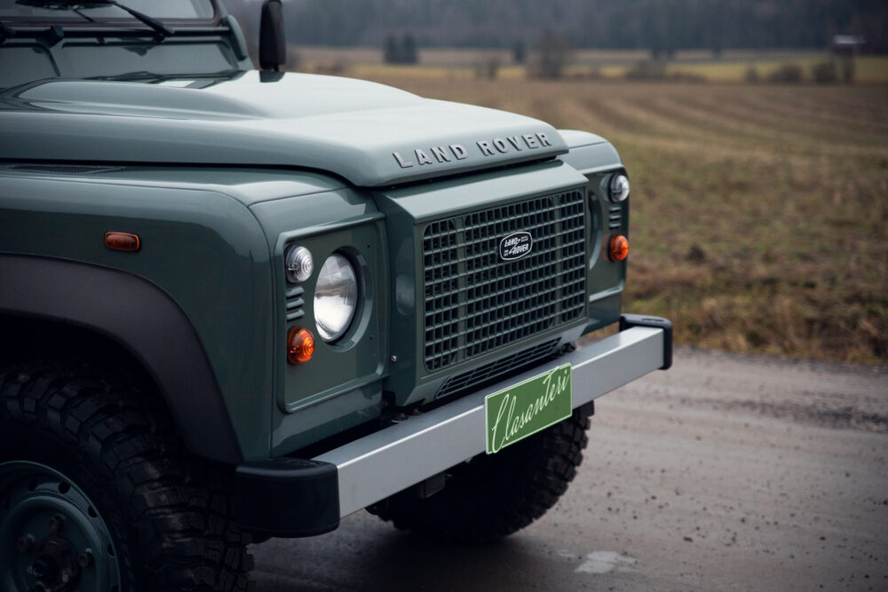 Green Land Rover Defender on rural road