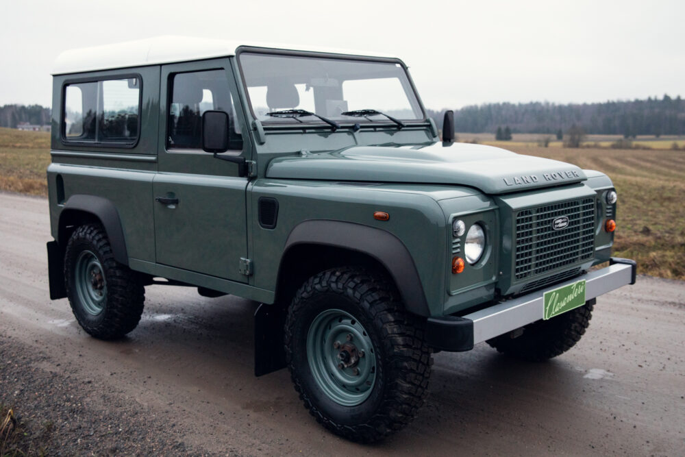 Green Land Rover Defender on rural road