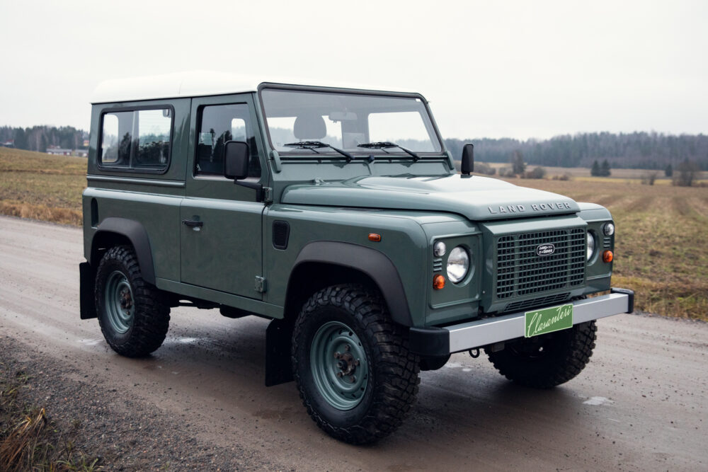 Green Land Rover Defender on rural road