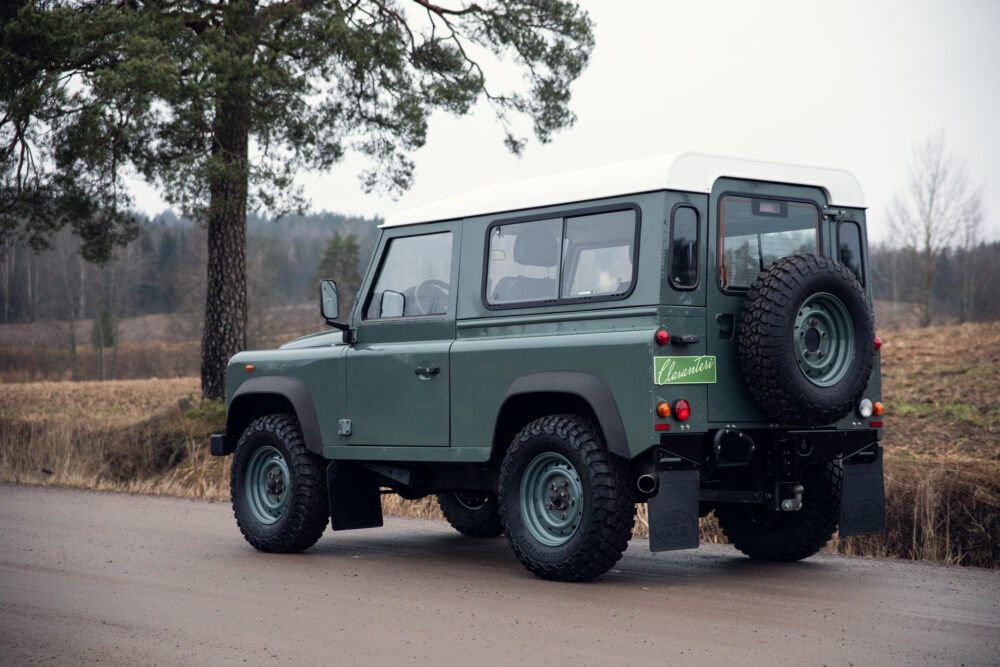 Green classic SUV on rural road near forest