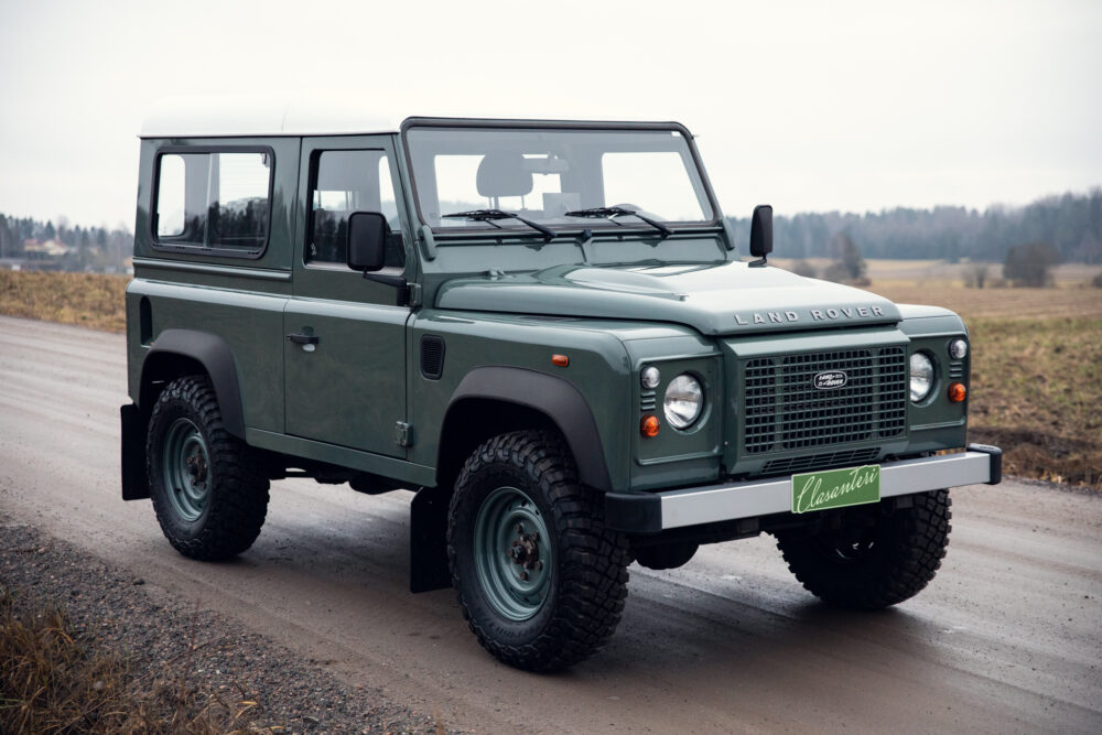 Green Land Rover Defender on rural road