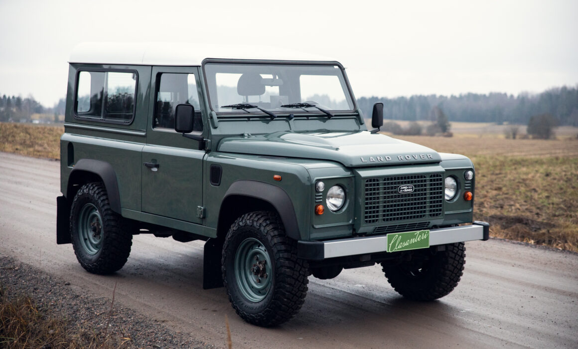 Green Land Rover Defender on rural road