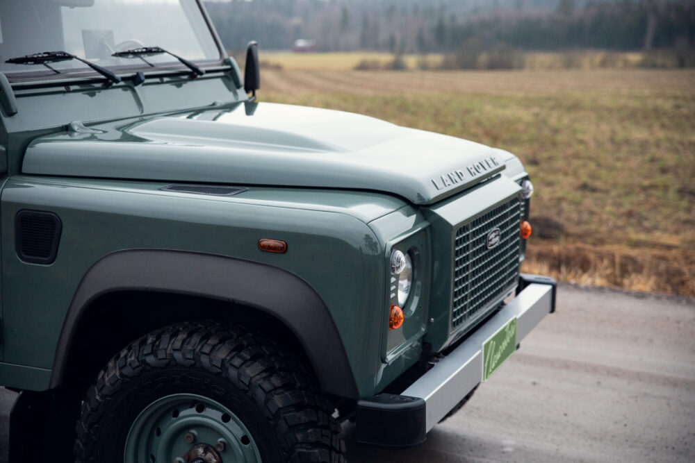 Green Land Rover Defender on countryside road