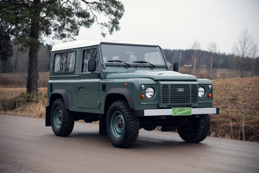 Green Land Rover Defender on rural road
