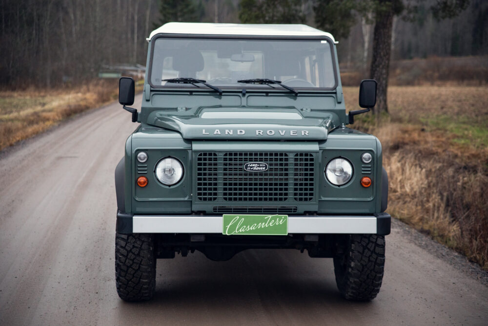 Green Land Rover Defender on a rural road