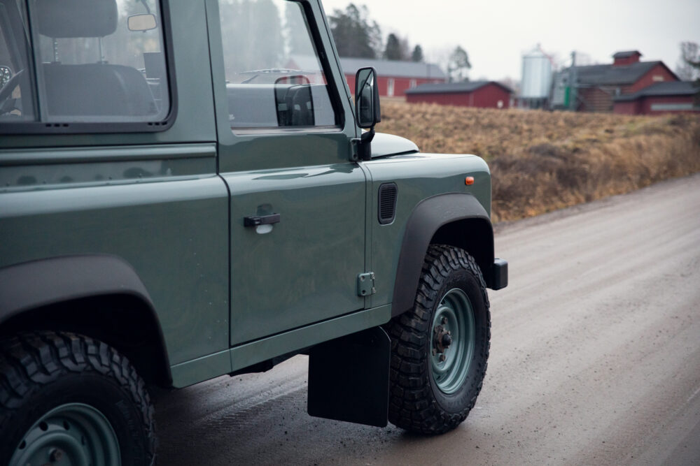 Green off-road vehicle near farms on rural road
