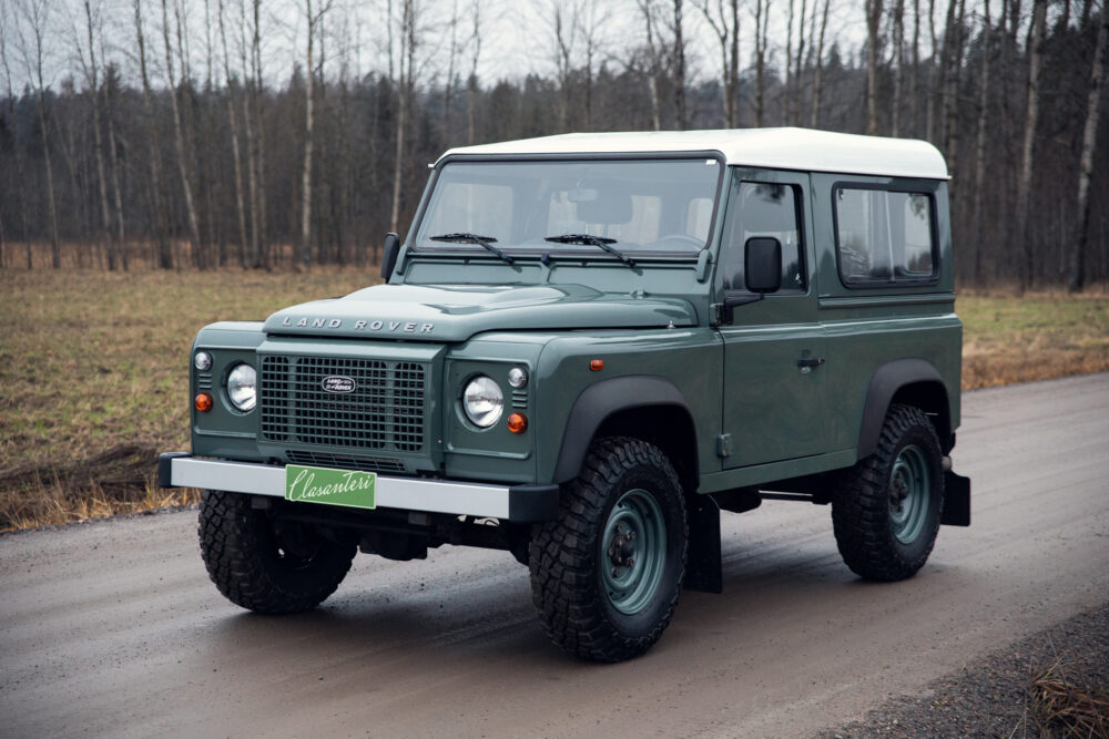 Green Land Rover Defender on rural road