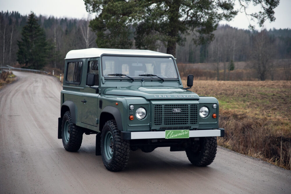 Green Land Rover Defender on country road