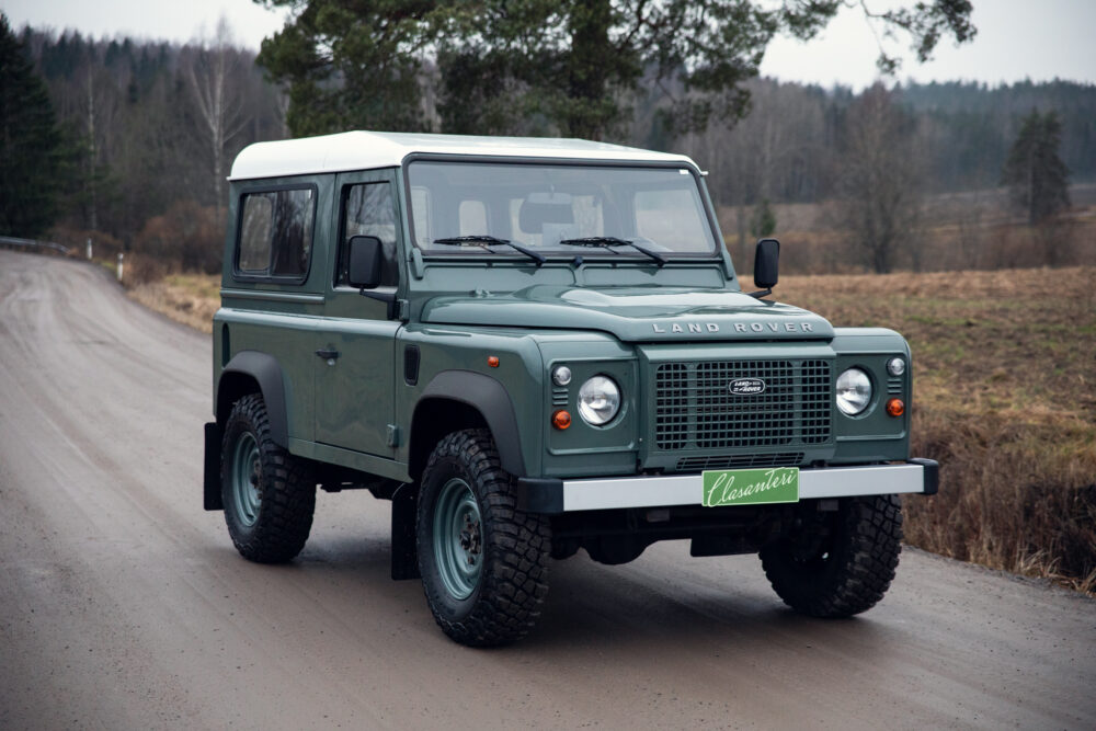 Green Land Rover Defender on rural road