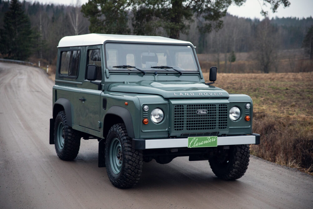Green Land Rover Defender on rural road