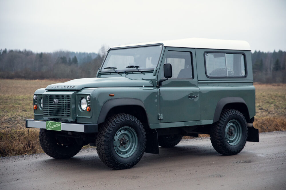 Green Land Rover Defender on rural road
