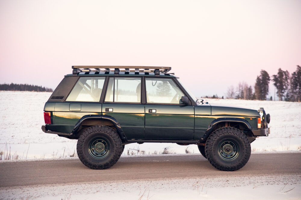 Green SUV on snowy road at dusk