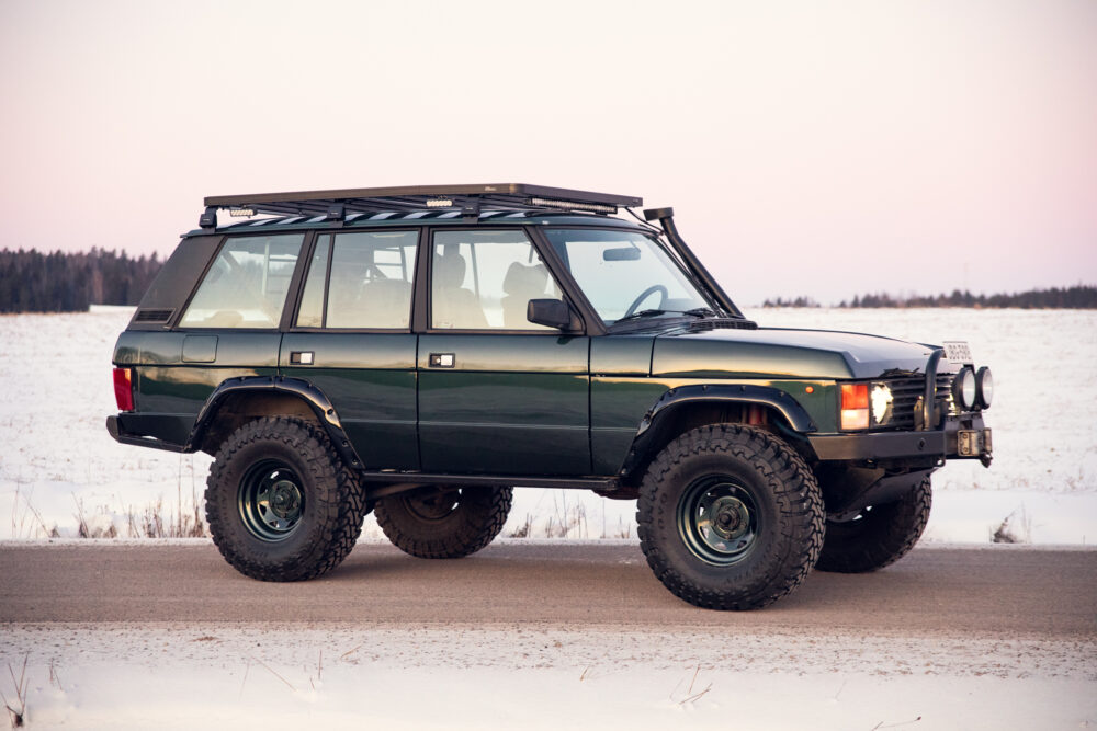 Modified green SUV on snowy landscape at dusk