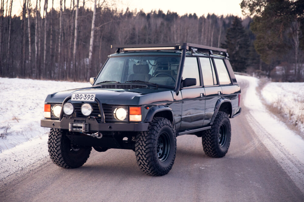 Black SUV on snowy forest road at dusk