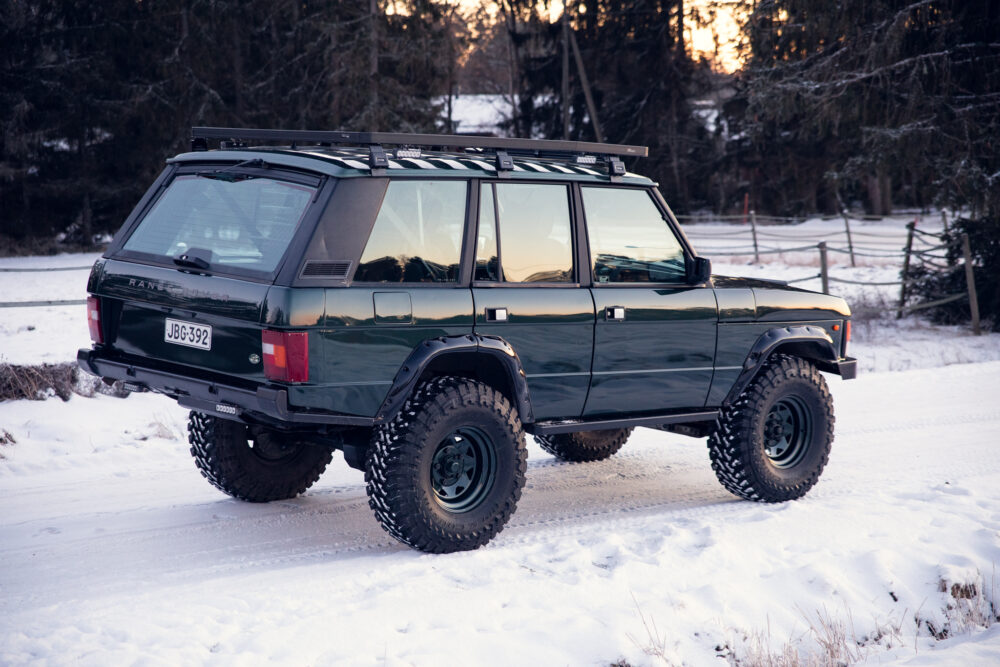 Green SUV on snowy road at sunset