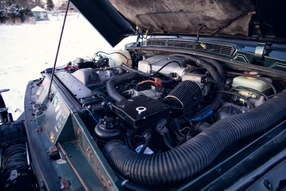 Open car hood showing detailed engine components in snow