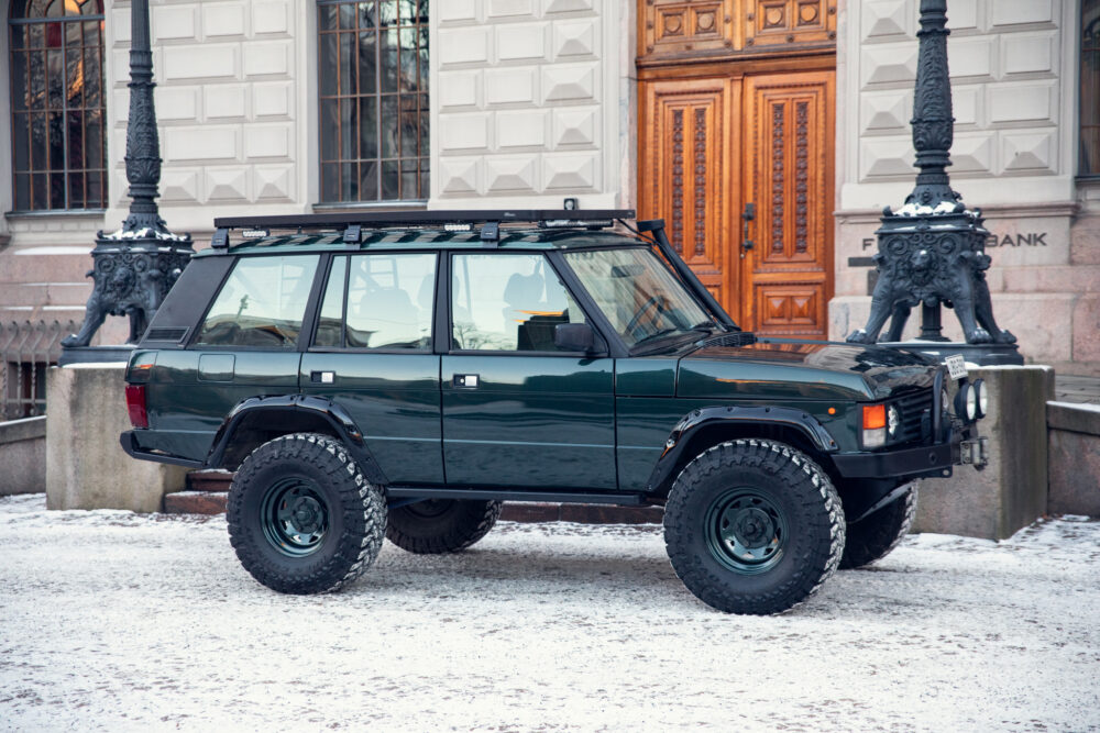 Green SUV parked on snowy street near historic building