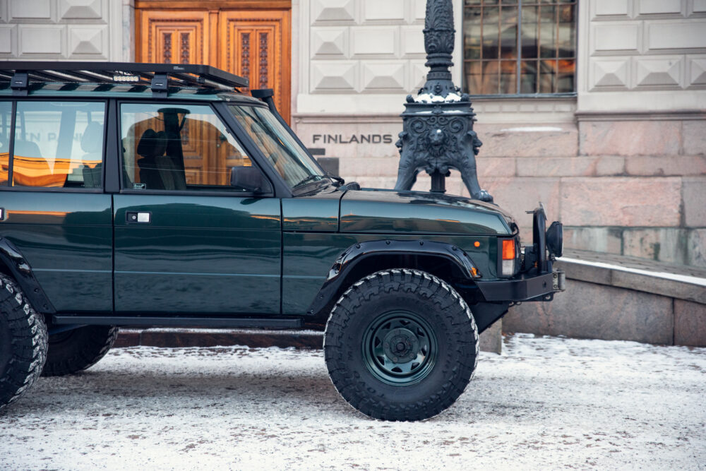 Green off-road vehicle near snow-covered statue