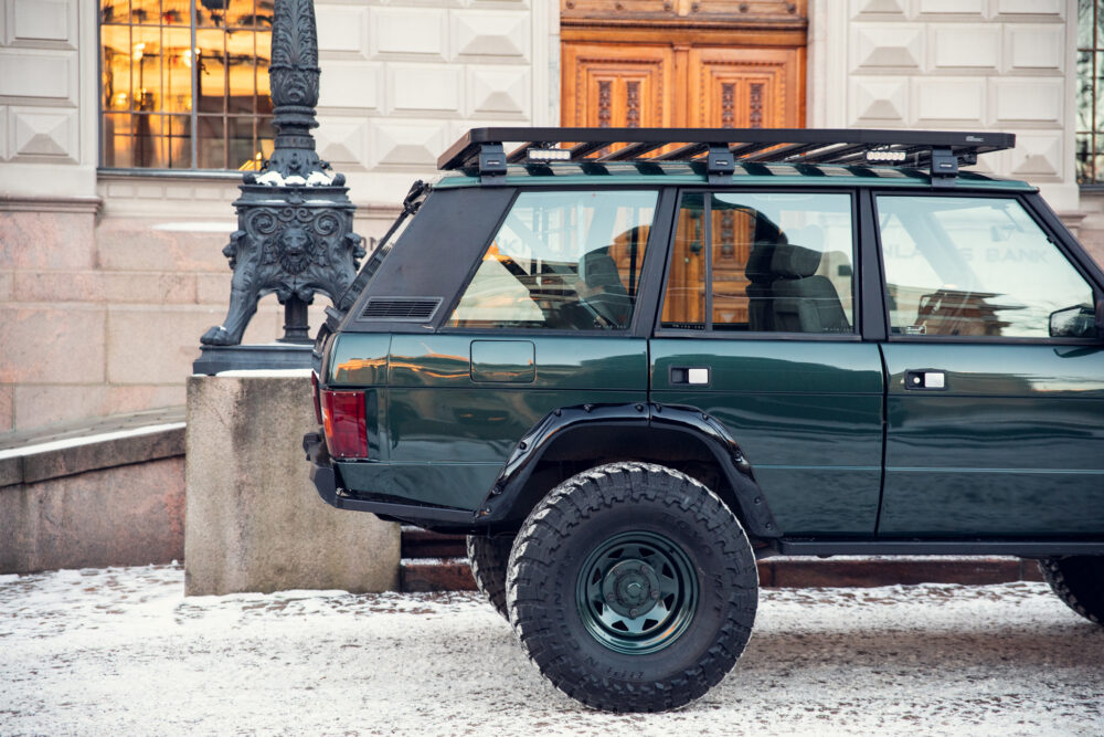 Green SUV parked near ornate lamp post and building