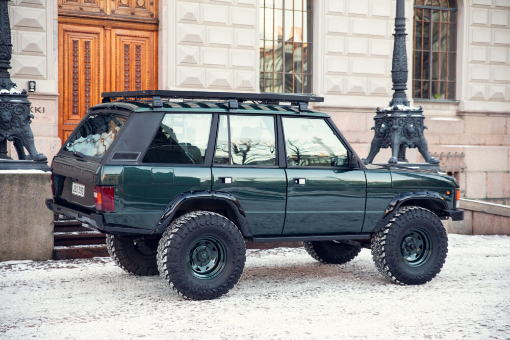 Green SUV parked near historical building on snowy day