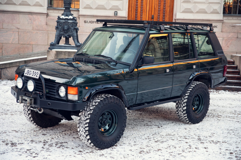 Black SUV parked on snowy street near elegant building