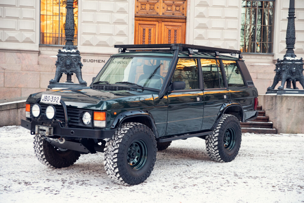 Modified SUV parked on snowy street near ornate building