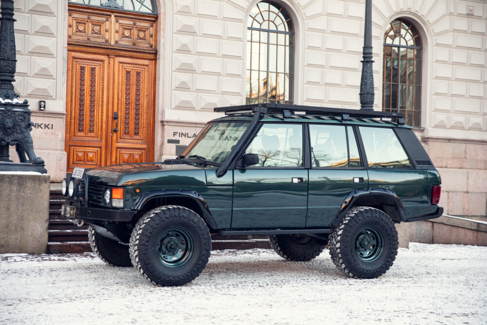 Green SUV parked near historic building on snowy day
