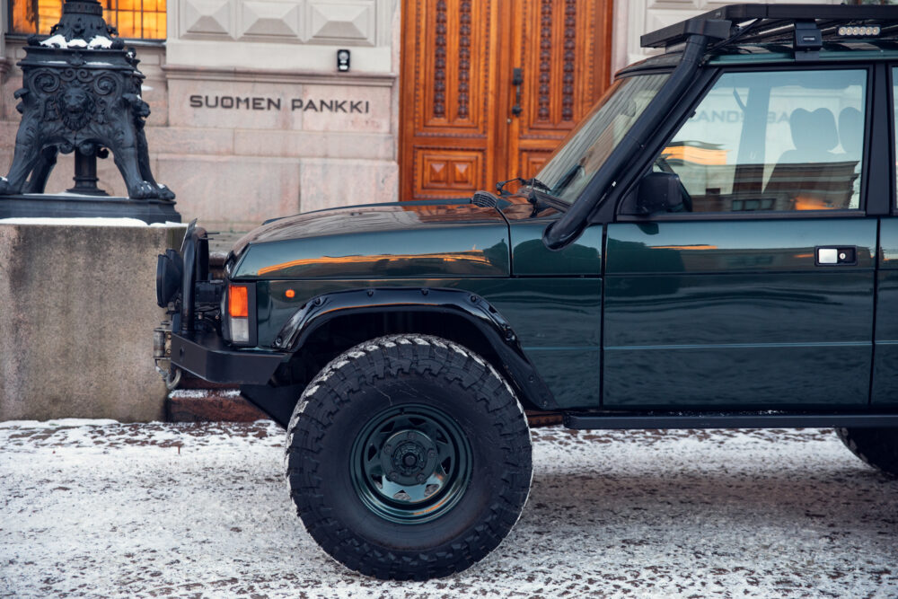 Dark green SUV parked in snowy setting near building