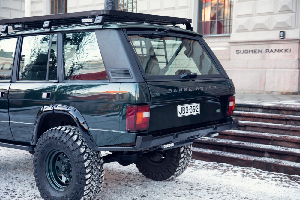 Vintage Range Rover parked near stone steps in winter.
