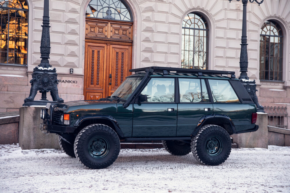 Green SUV parked on snowy street near historical building
