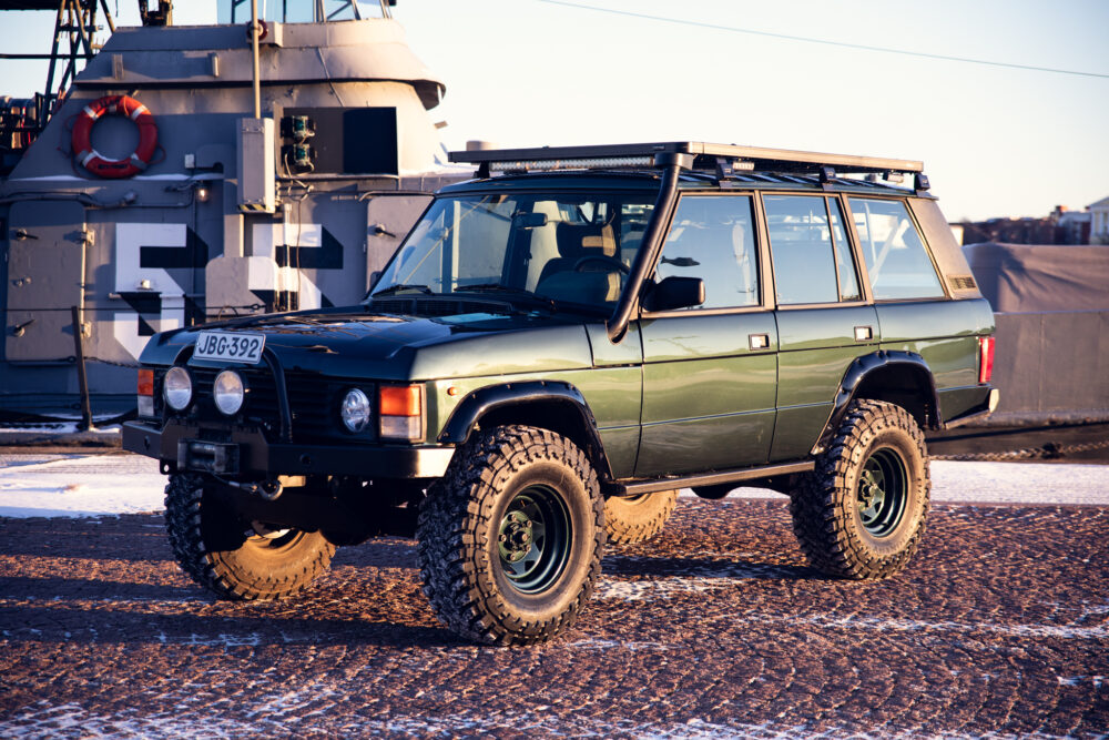 Green off-road vehicle near ship during sunset