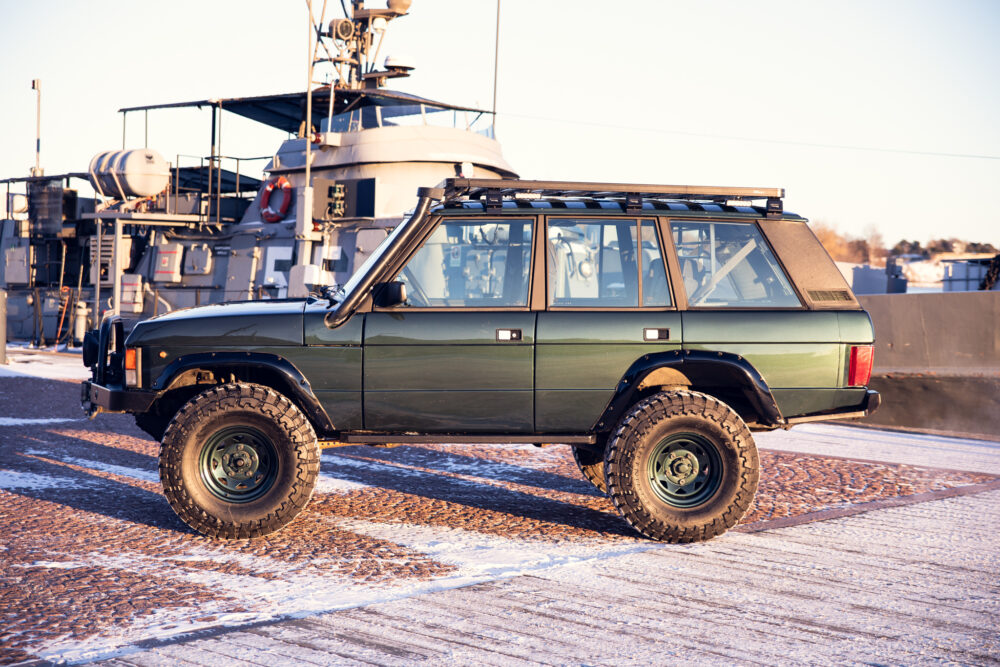 Green SUV near ship on snowy dock at sunset