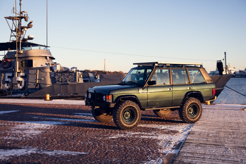 Green SUV parked near navy ship on snowy dock