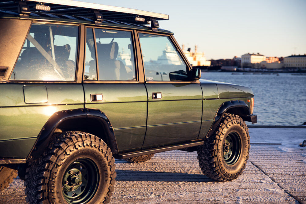 Green SUV parked at sunset by waterfront