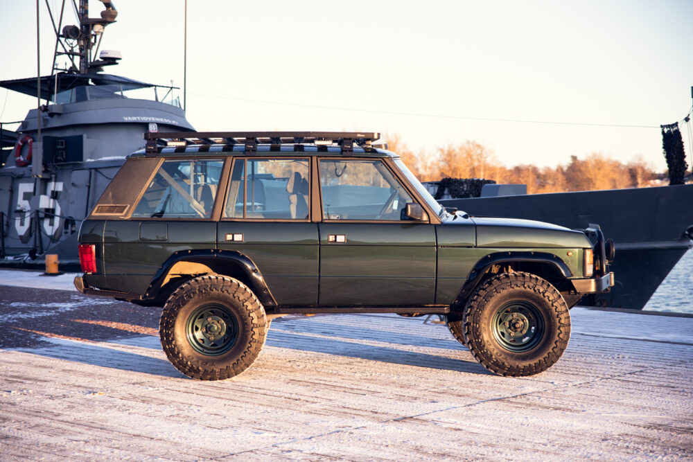 Modified green SUV near naval ship on icy dock
