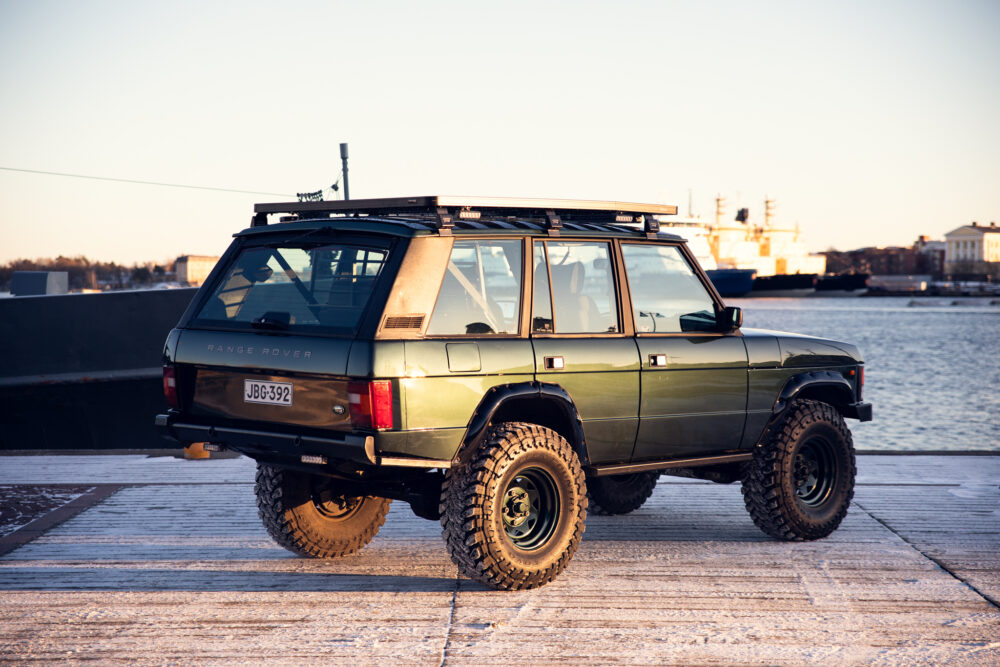 Green Range Rover near water during sunset