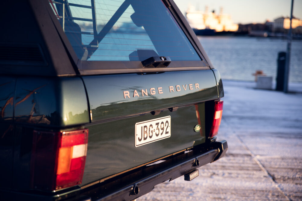 Green Range Rover near water at sunset