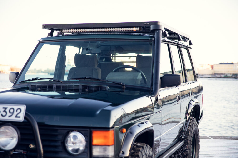 Black SUV parked near water at sunset