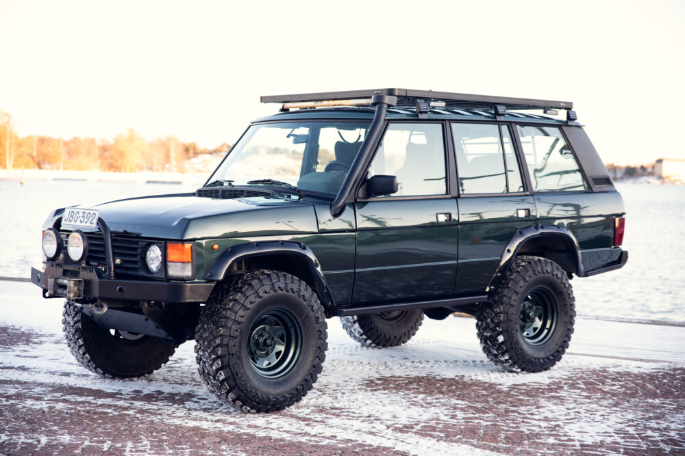 Green SUV parked on snowy lakeside terrain
