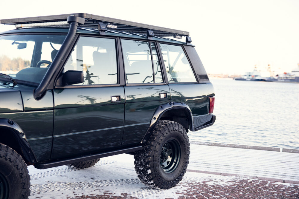 Green off-road SUV parked by snowy waterfront
