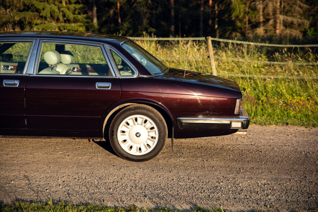 Vintage maroon sedan parked on gravel roadside