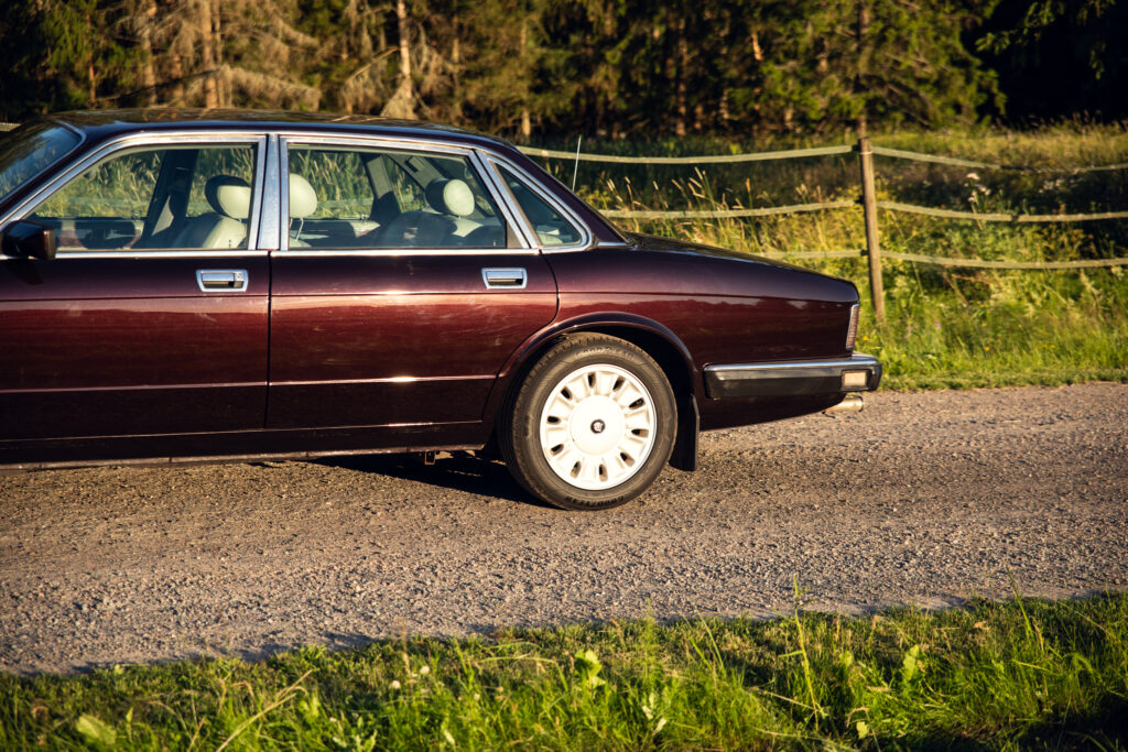 Maroon vintage sedan parked on gravel road