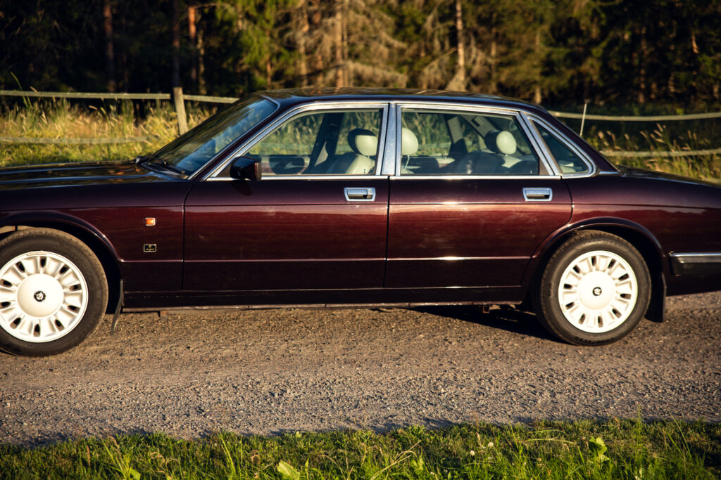 Maroon luxury sedan parked on rural roadside
