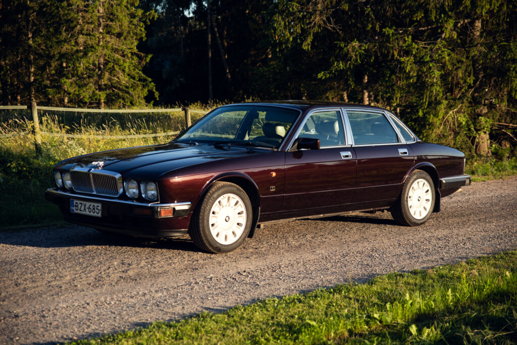 Classic maroon luxury sedan parked on gravel road