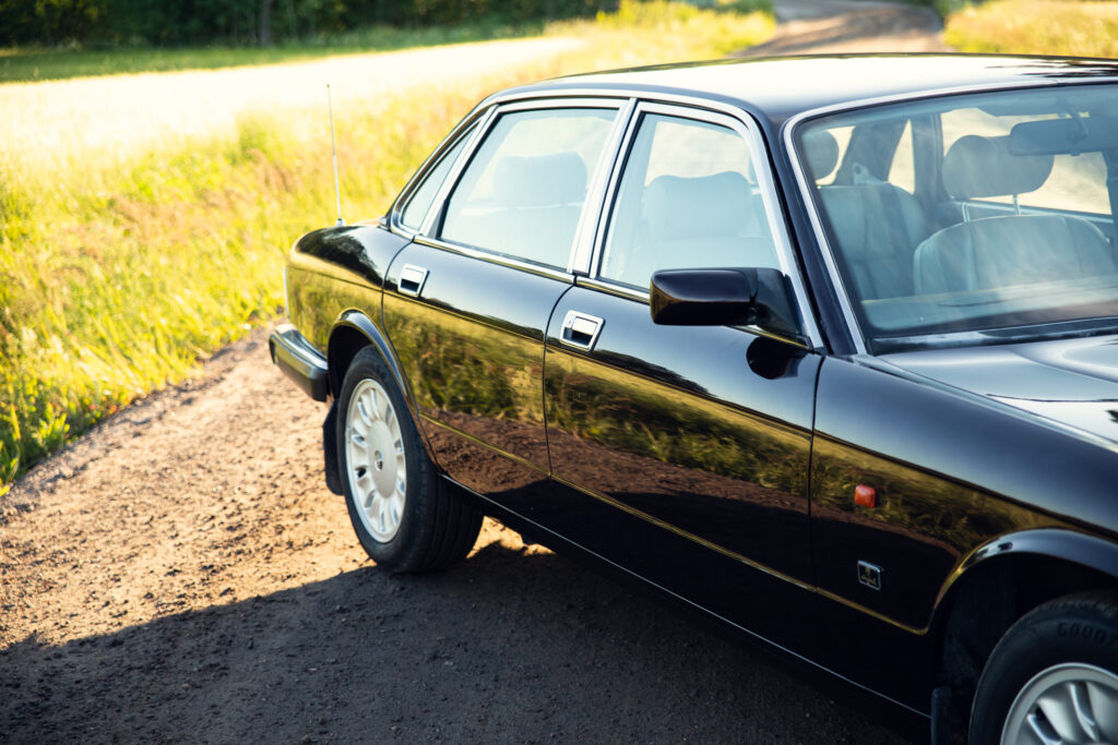 Black sedan parked on sunny rural dirt road