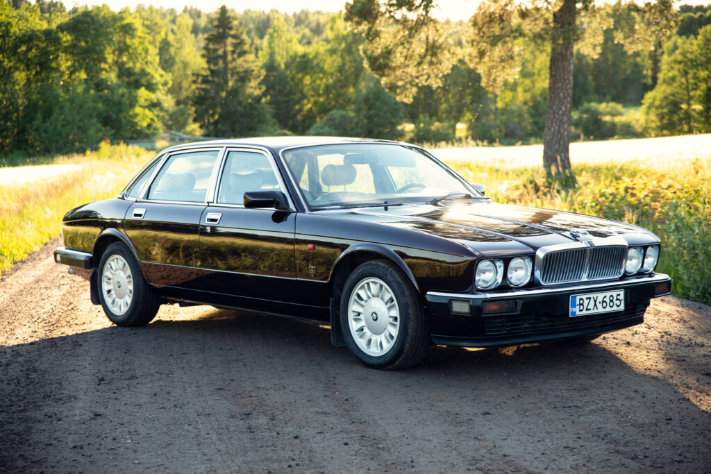 Black classic luxury sedan on rural road
