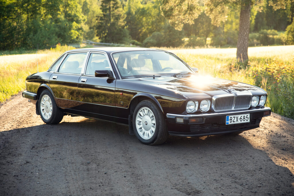 Classic black luxury sedan on sunlit country road